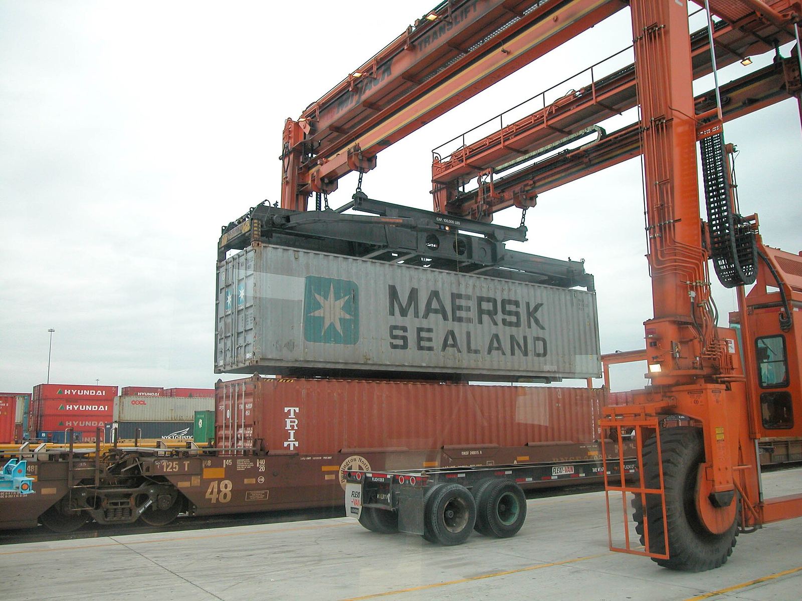 A shipping container being lifted onto a chassis at an intermodal yard.